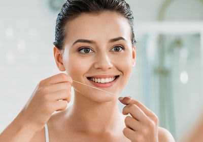 Lächelnde Frau mit Zahnseide in den Händen