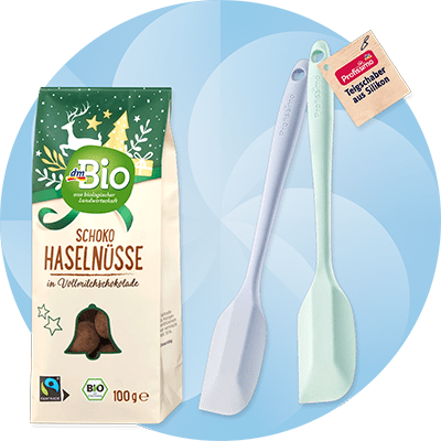 Confezione di nocciole ricoperte di cioccolato dmBio e spatole in silicone Profissimo su sfondo azzurro con elementi astratti bianchi