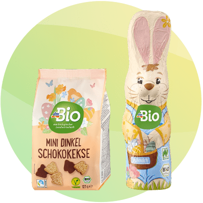 Confezione di biscotti e cioccolato a forma di coniglio a marchio dmBio su sfondo verde sfumato