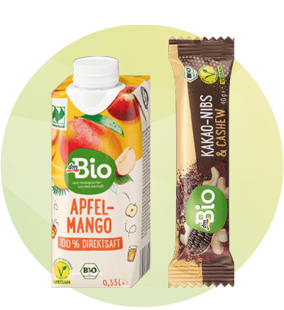 Bevanda di succo di mela e mango e barretta di cacao e anacardi dmBio su sfondo verde