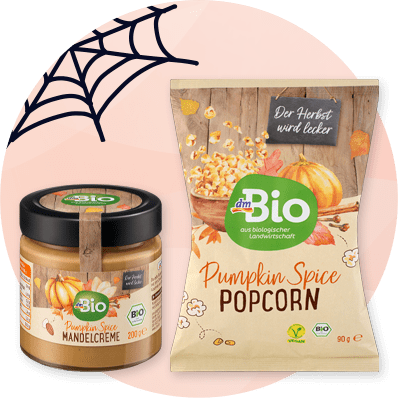 Prodotti dmBio con zucca: burro di arachidi e popcorn su sfondo arancione con ragnatela nera