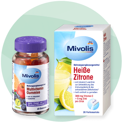 Integratori Mivolis multivitaminici e bevanda al limone per raffreddore su sfondo verde sfumato