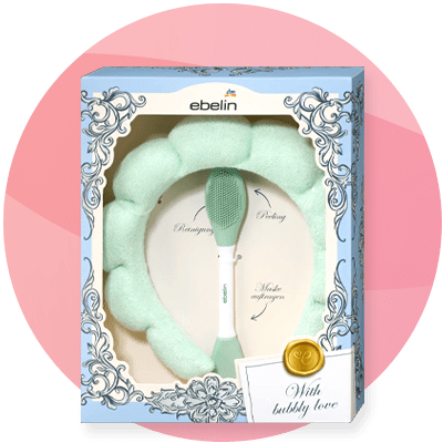 Set di bellezza con spazzola viso e fascia verde a marchio ebelin su sfondo rosa sfumato