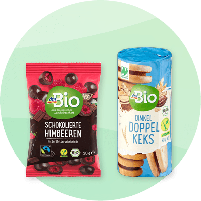 Prodotti dmBio: lamponi al cioccolato e biscotti vegani al farro e cioccolato su sfondo verde sfumato