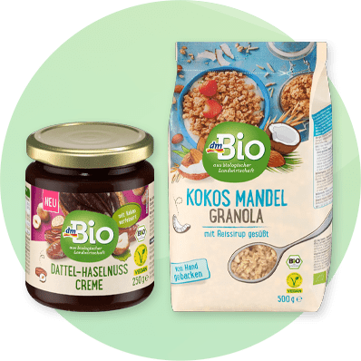 Prodotti dmBio: crema spalmabile di datteri e nocciole e granola di cocco e mandorle su sfonfo verde sfumato