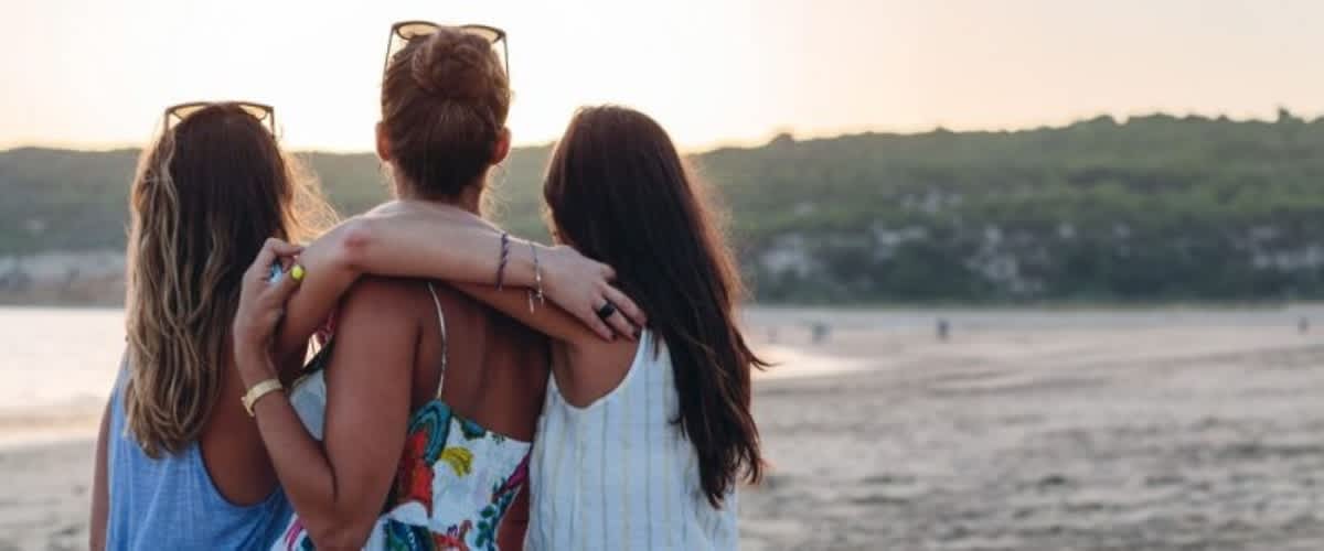 Tre donne abbracciate sulla spiaggia