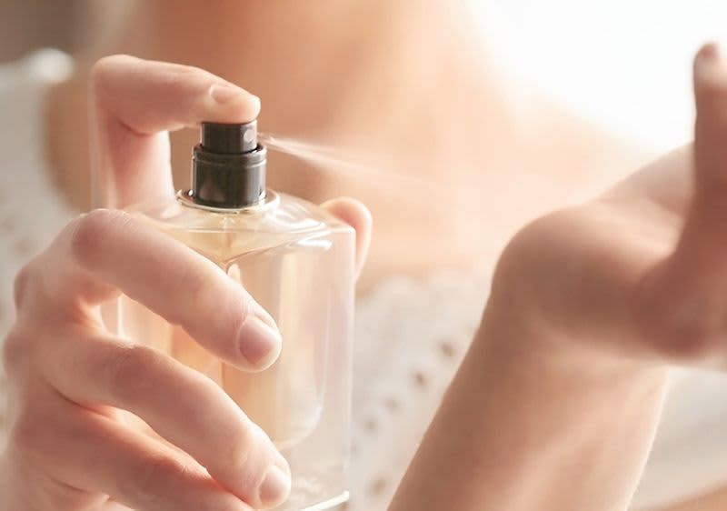 Frau sprüht Duft auf Handgelenk