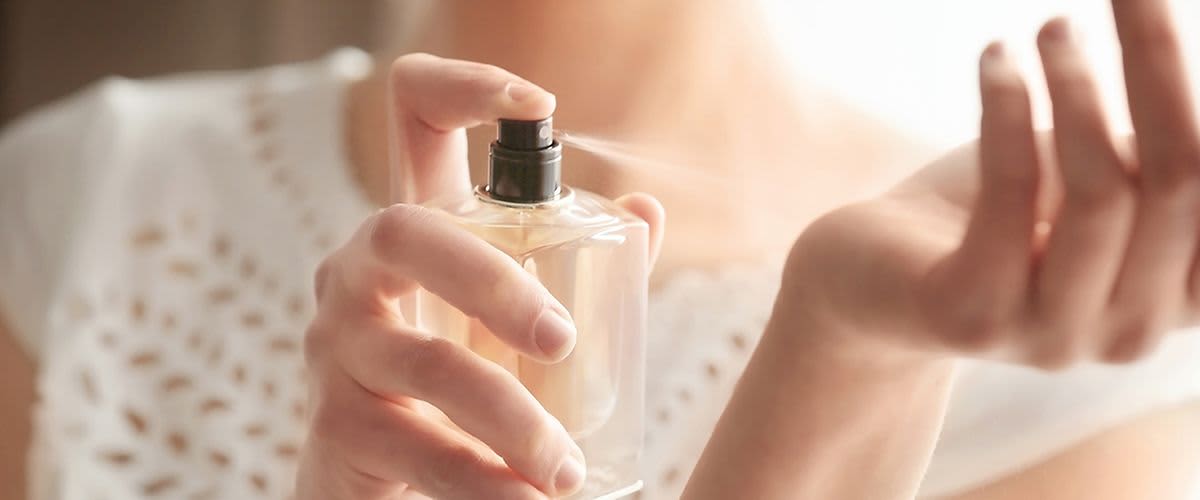 Frau sprüht Duft auf Handgelenk