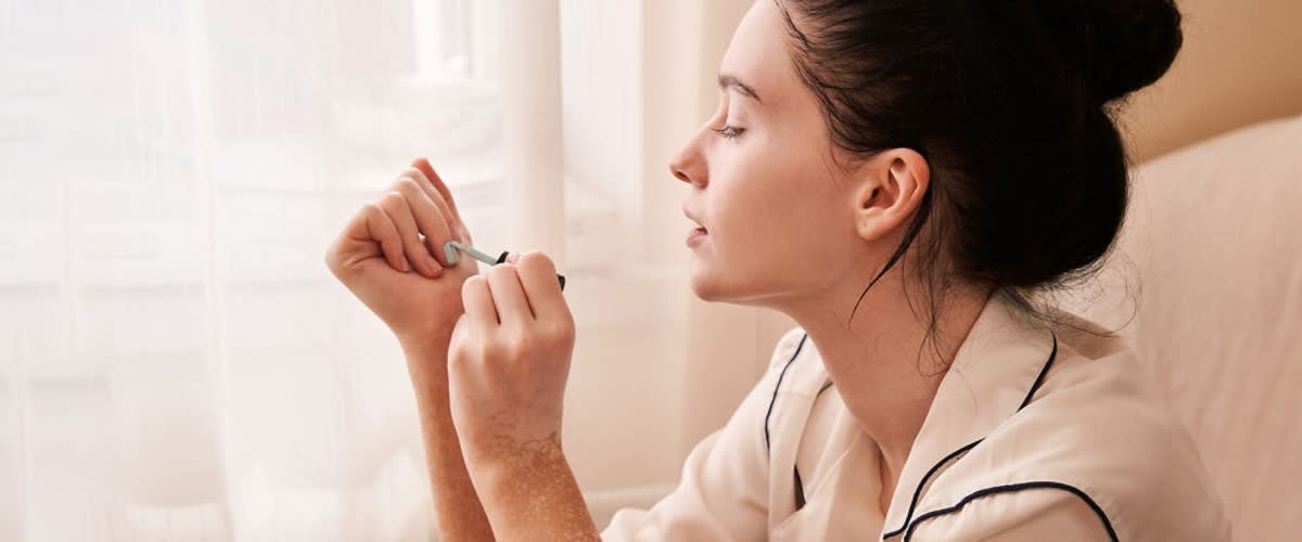 Ragazza si fa manicure in casa e si applica smalto su unghie