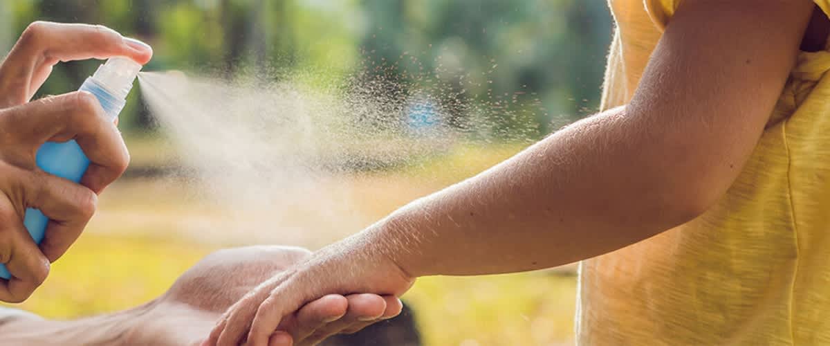 Genitore spruzza spray repellente per insetti sul braccio di un bambino all'aperto