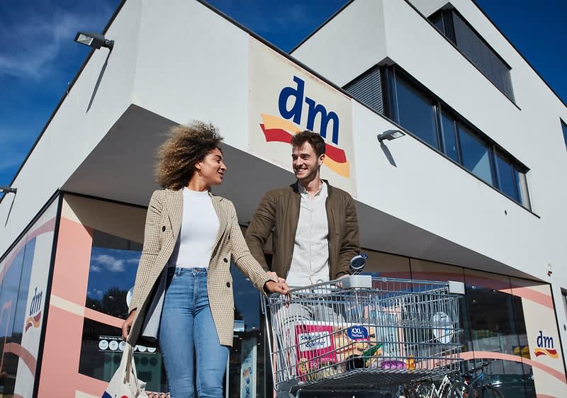 Due clienti davanti ad un punto vendita dm con carrello