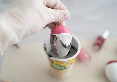 Hand taucht Ei in Becher