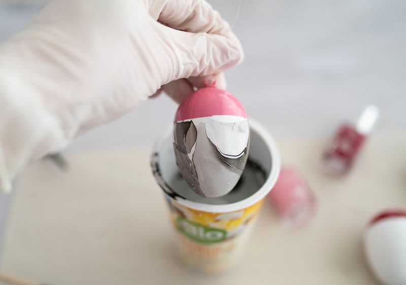 Hand taucht Ei in Becher