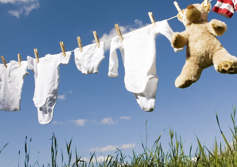 Babykleidung auf einer Wäscheleine im grünen aufgehängt