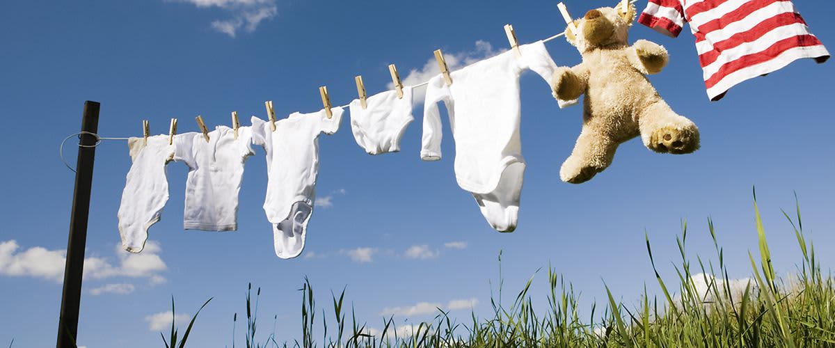 Babykleidung auf einer Wäscheleine im grünen aufgehängt