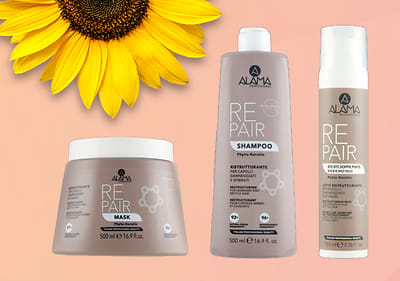 Prodotti per capelli Alama Professional linea Repair: maschera, shampoo e schiuma su sfondo rosa sfumato con girasole