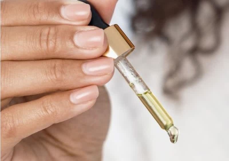 Mano che tiene un contagocce con siero all'acido ialuronico