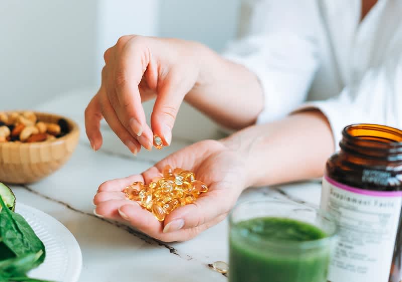 Integratori alimentari con capsule e frullato verde su tavolo