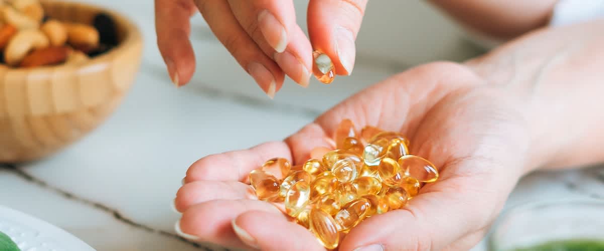 Integratori alimentari con capsule e frullato verde su tavolo