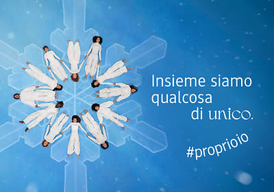 Persone in cerchio creano un fiocco di neve su sfondo blu con scritta 'Insieme siamo qualcosa di unico' #proprioio