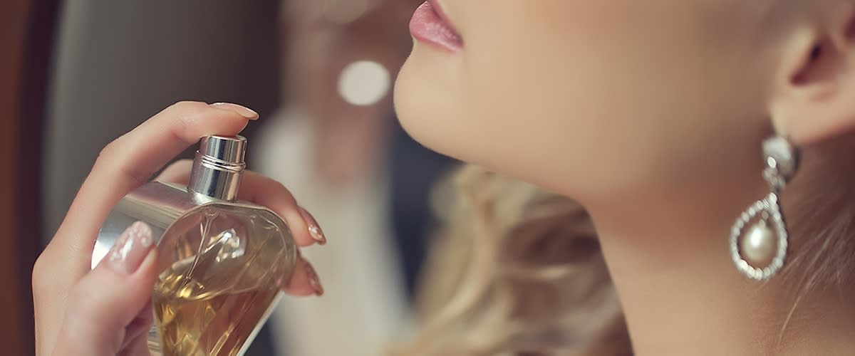 Frau sprüht Duft auf ihren Hals