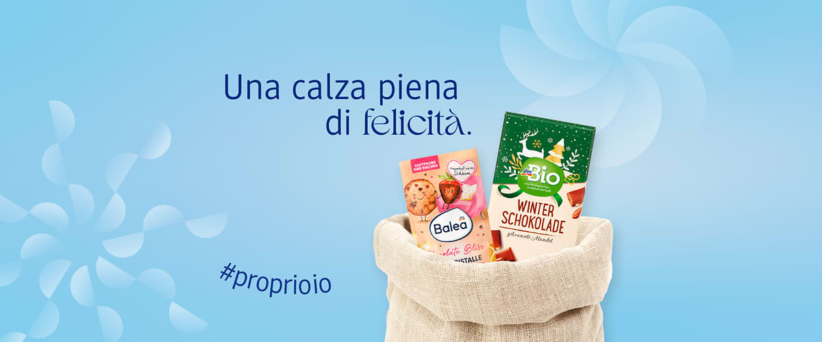 Calza della befana con sali da bagno Balea e tavoletta di cioccolato dmBio su sfondo azzurro con elementi astratti bianchi