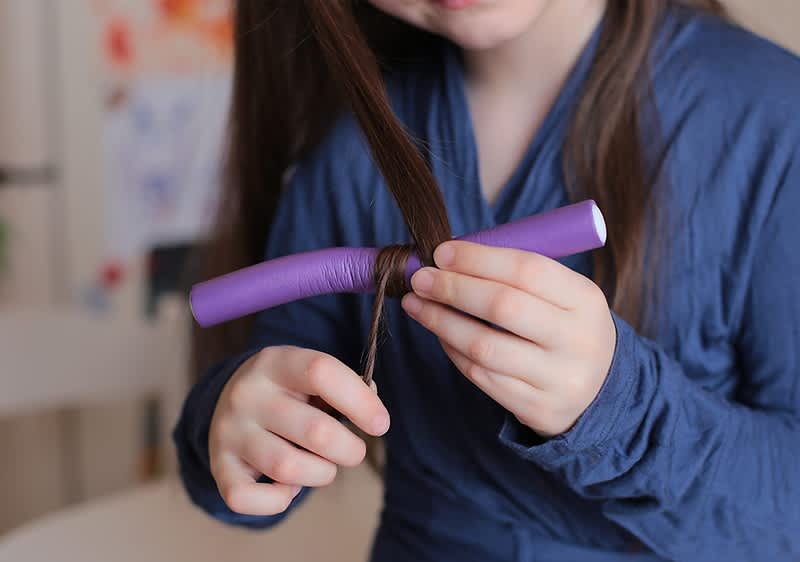 Bambina che si arriccia i capelli con bigodini
