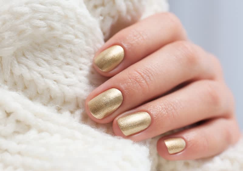Mano con unghie laccate in oro