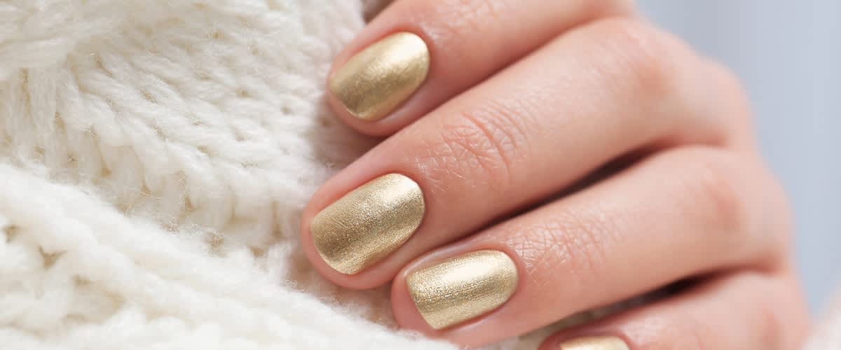 Mano con unghie laccate in oro