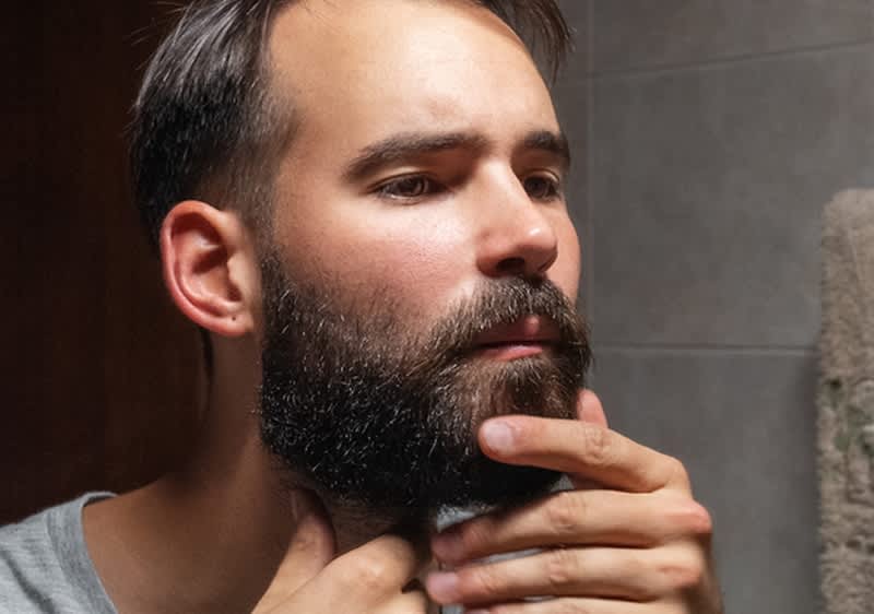 Uomo allo specchio che si sistema la barba