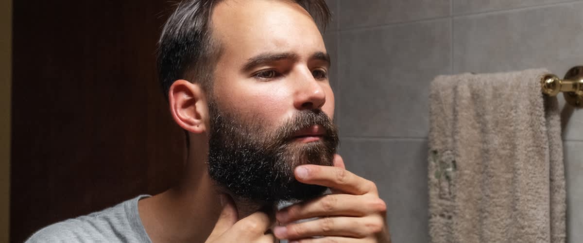 Uomo allo specchio che si sistema la barba