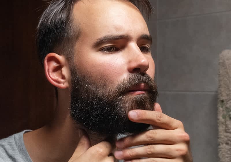 Uomo allo specchio che si sistema la barba
