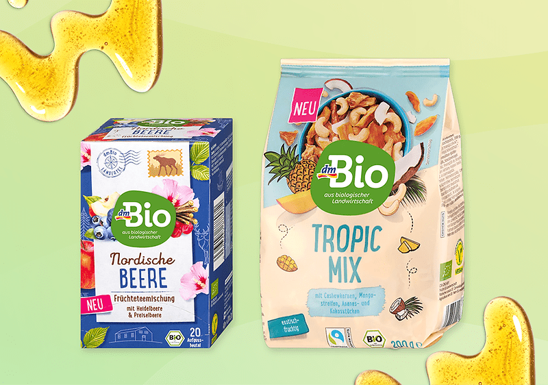 Confezione di tè ai frutti rossi e mix di frutta secca tropicale a marchio dmBio su sfondo verde con miele