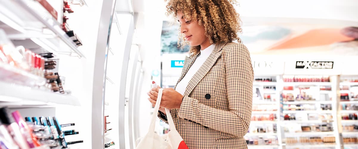 Una donna sta facendo shopping in un negozio di cosmetici, tenendo una borsa in mano.