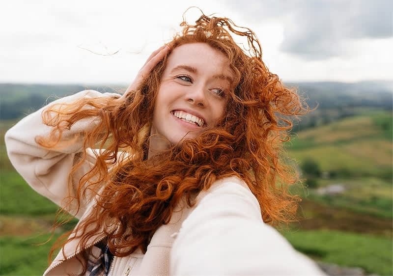 Capelli ricci rossi in un paesaggio naturale