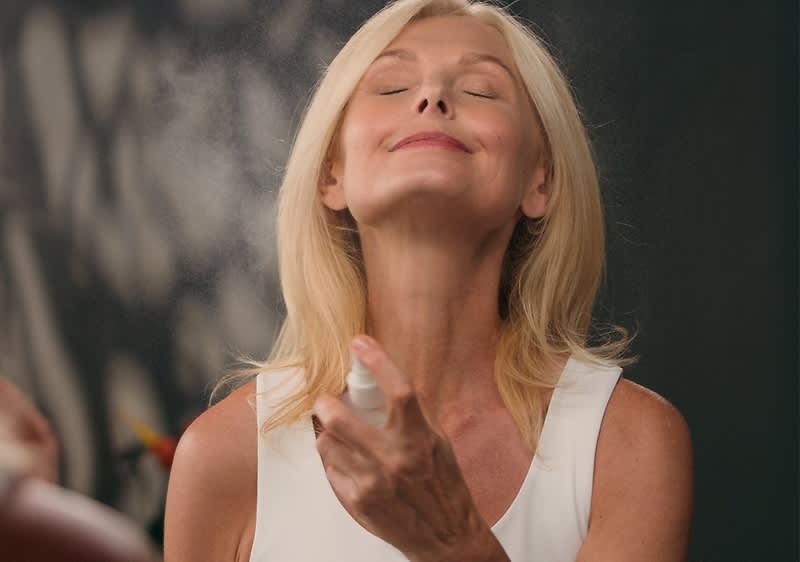 Donna che applica spray per il corpo