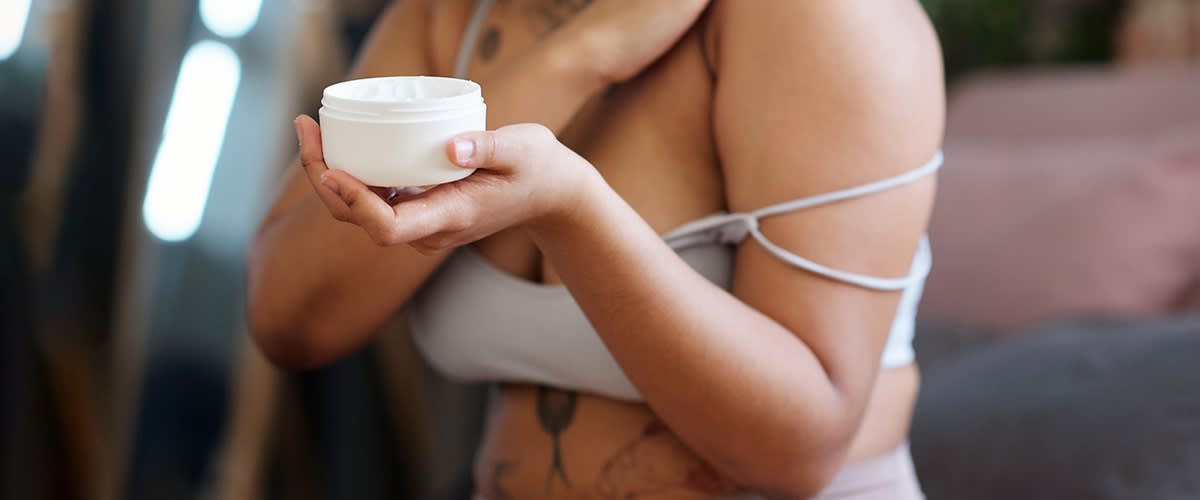 Donna che si mette la crema sul corpo