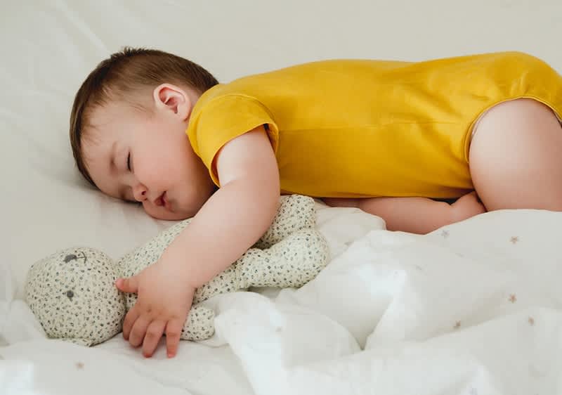 bebè dorme con un orsetto peluche