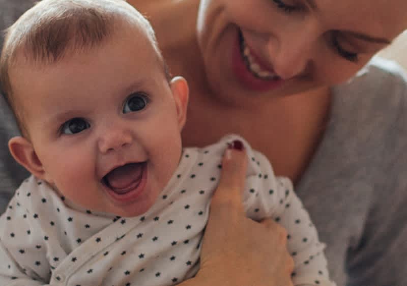 mamma sorridente tiene in braccio bebè che ride