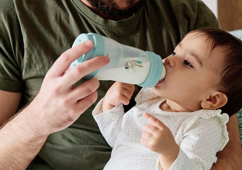 papà dà il latte al bebè con il biberon