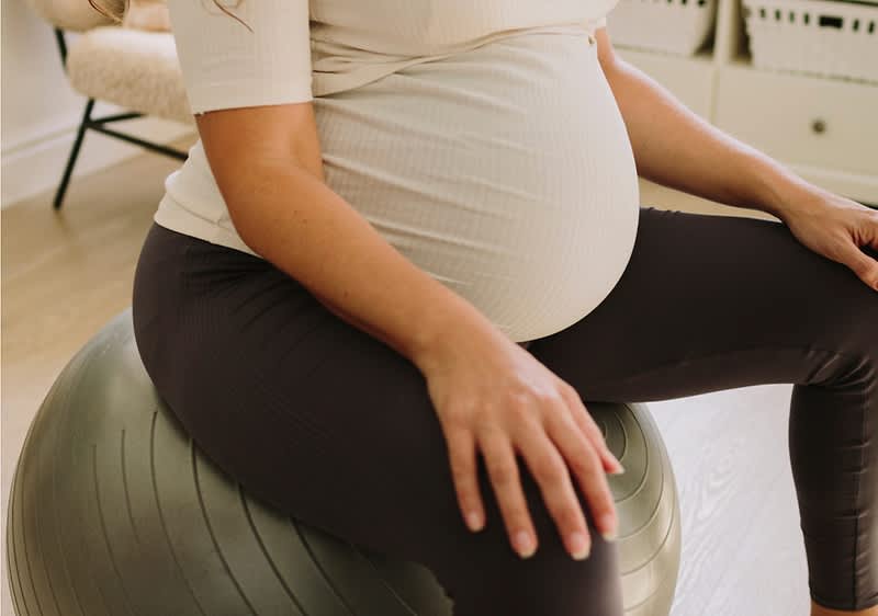 Donna incinta seduta su palla fitness