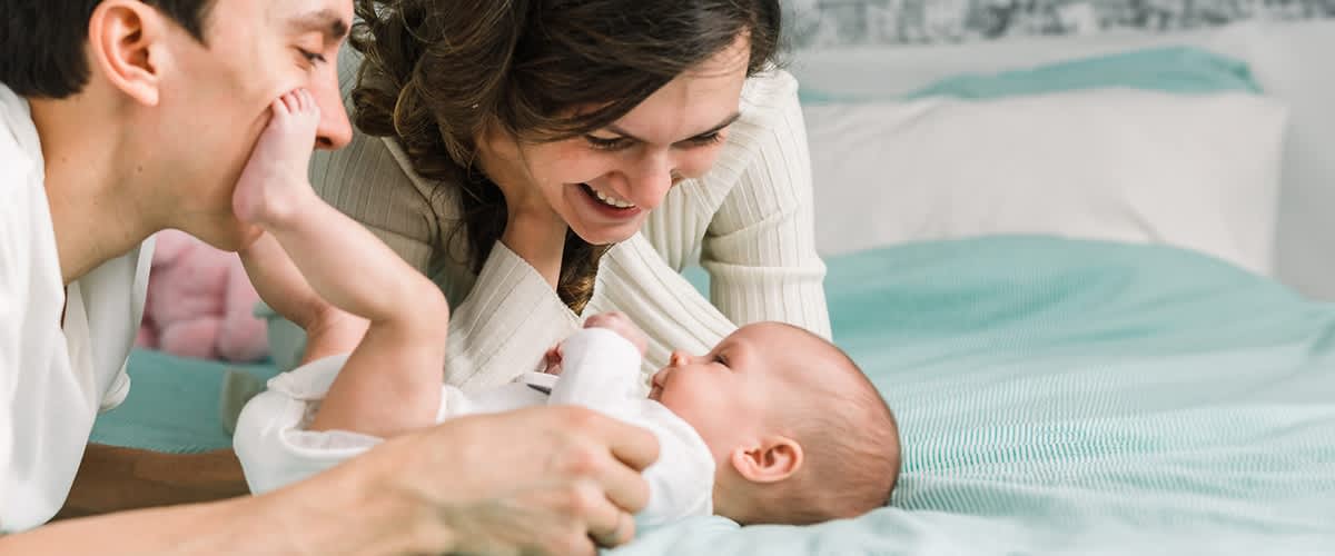 mamma e papà ridono con neonato