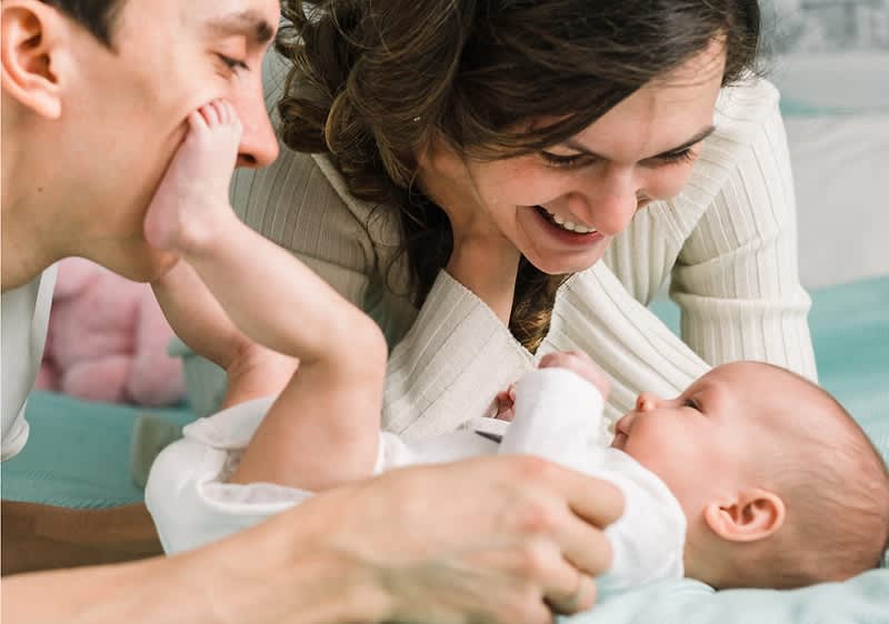 mamma e papà ridono con neonato