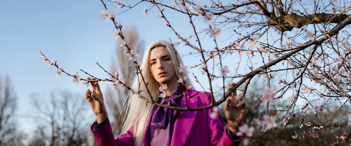 ragazzo con capelli biondo platino tra i ciliegi