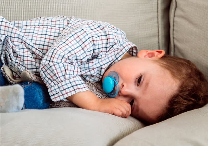 bambino con ciuccio su divano