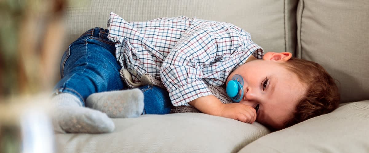 bambino con ciuccio su divano