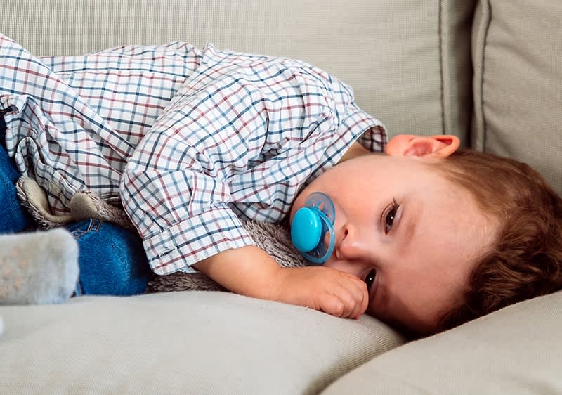 bambino con ciuccio su divano