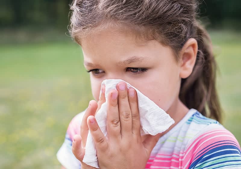 bambina si soffia il naso all'aperto