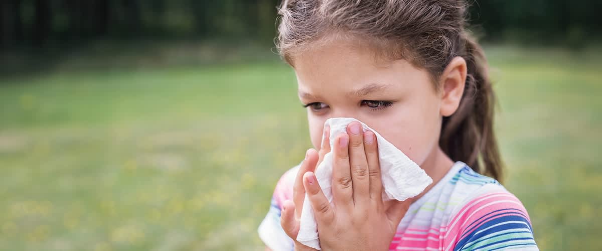 bambina si soffia il naso all'aperto