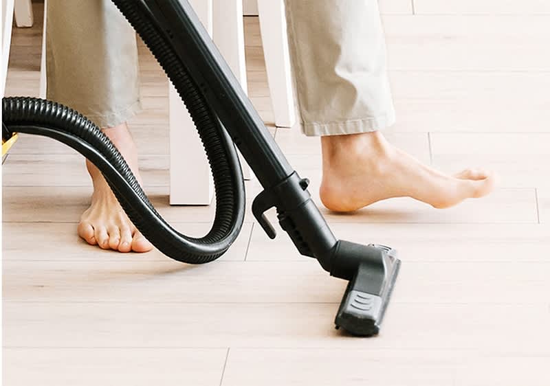 persona passa l'aspirapolvere sul pavimento